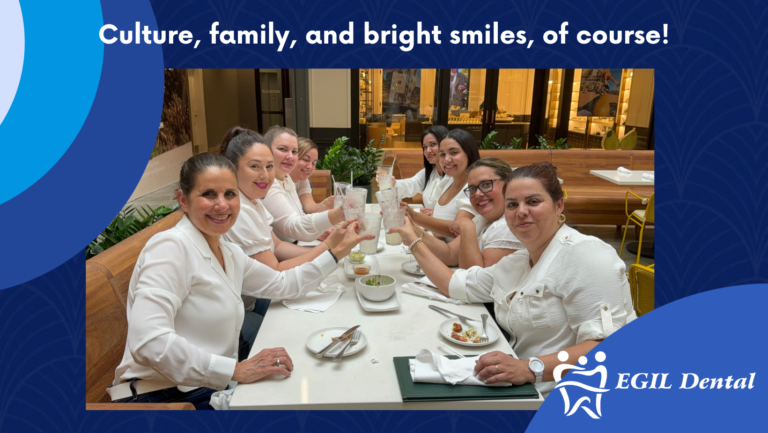 EGil Dental team members enjoying a meal together, smiling and raising their drinks in a celebratory toast.